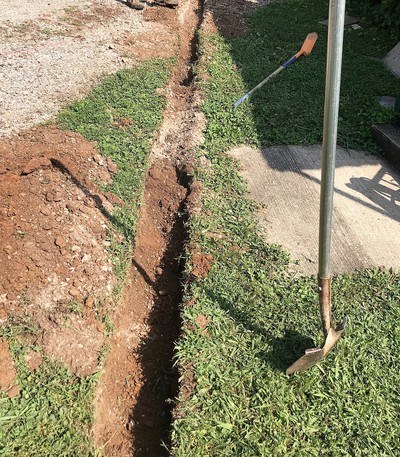 trench and shovel next to sidewalk 